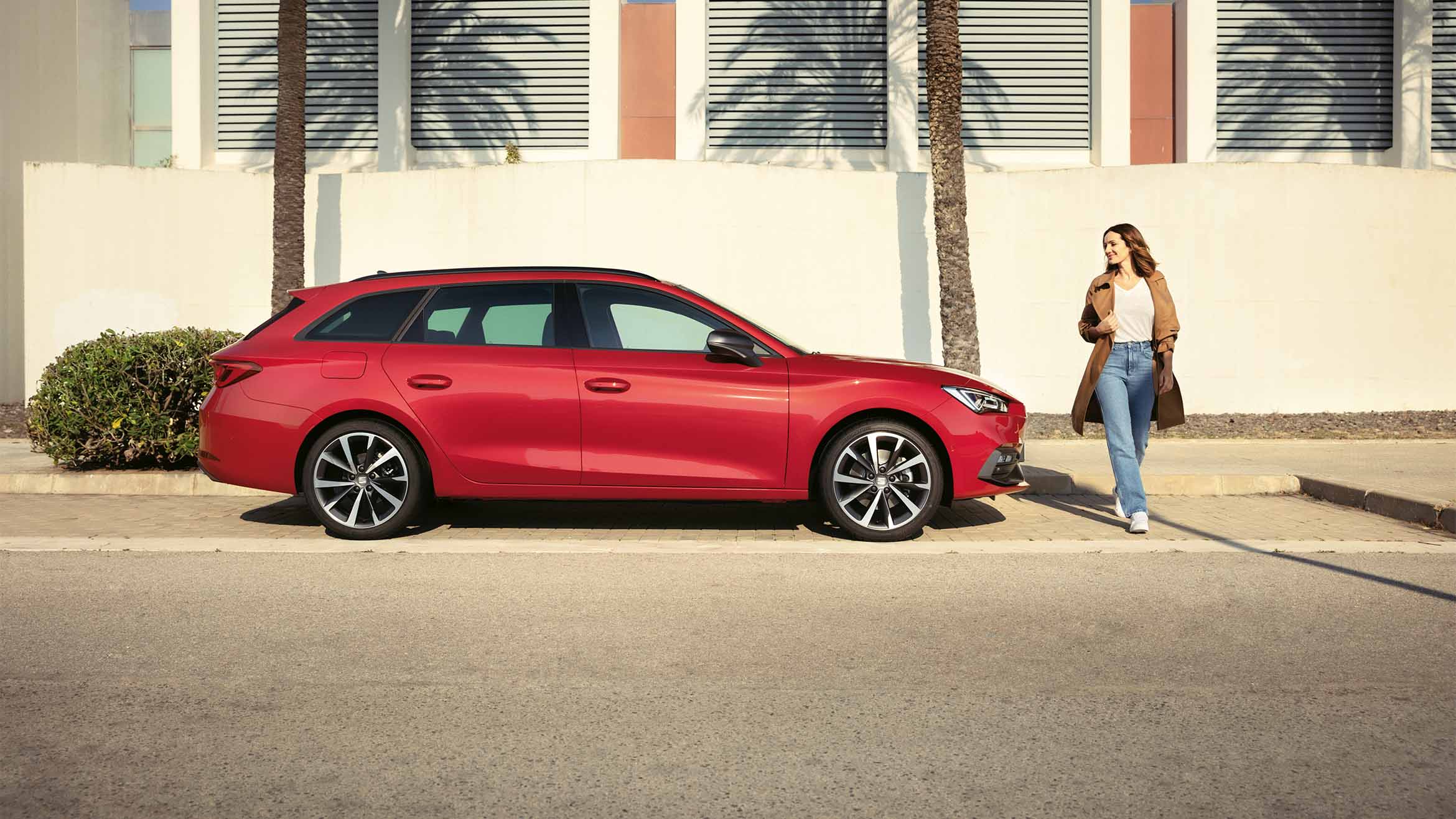 A red SEAT Leon SP Heather OW parked in a scenic outdoor location. The car features a spacious interior, sleek design, LED headlights and alloy wheels, ideal for families and long journeys.