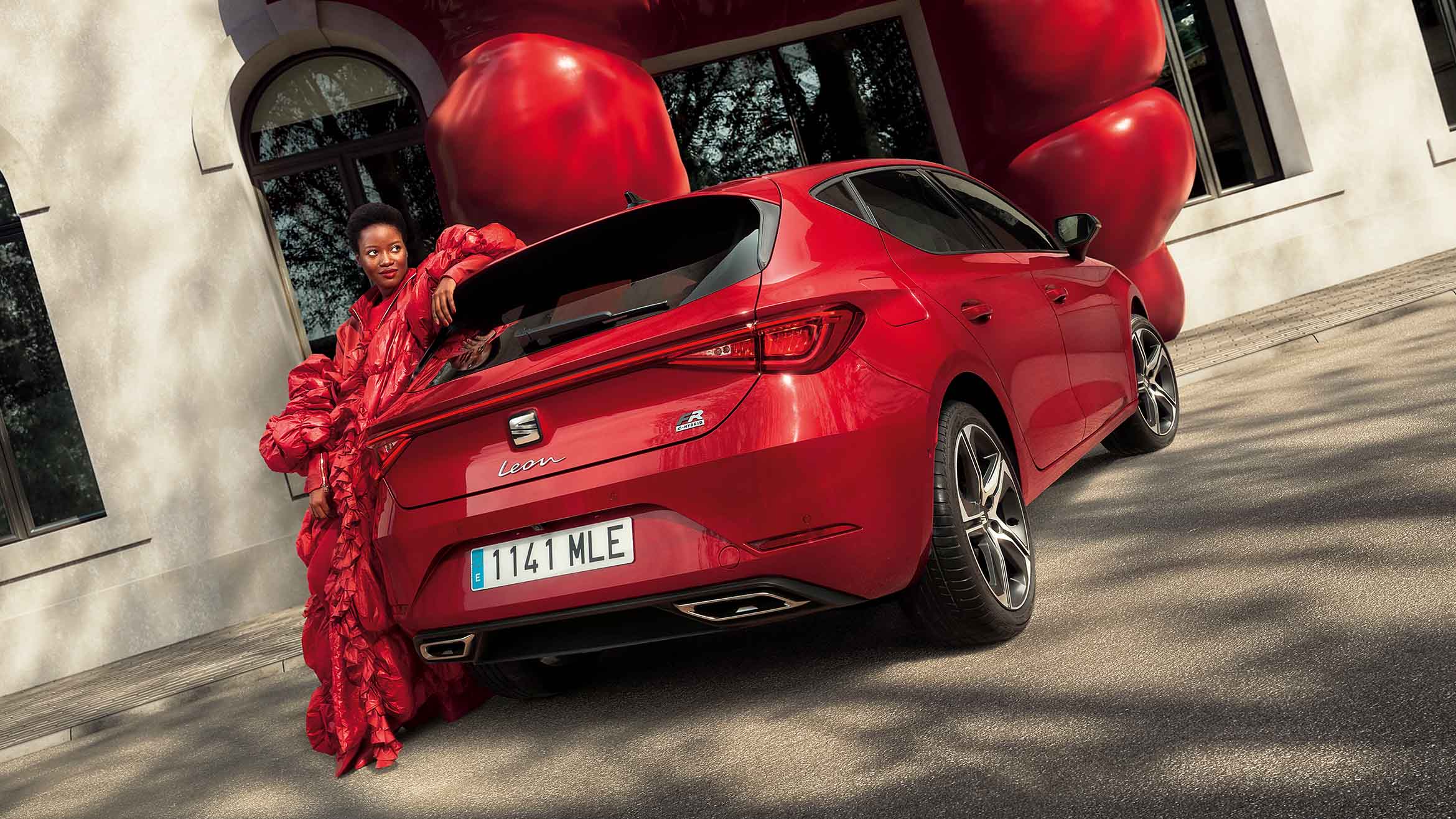 woman in a red coat standing next to seat leon desire red colour