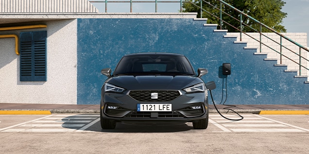 front view of a magnetic tech leon 5d, parked in front of a dark blue wall and staircase charging