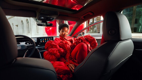 interior of a red leon 5d hybrid and a woman dressed in red, sitting on the copilots side looking at the back