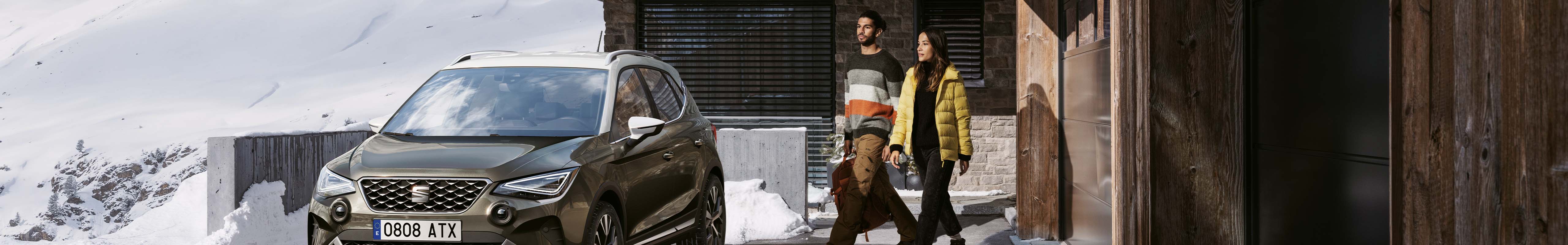 Seat ateca, one of seat’s end of life vehicles (elvs) parked outside wooden building by two models. 