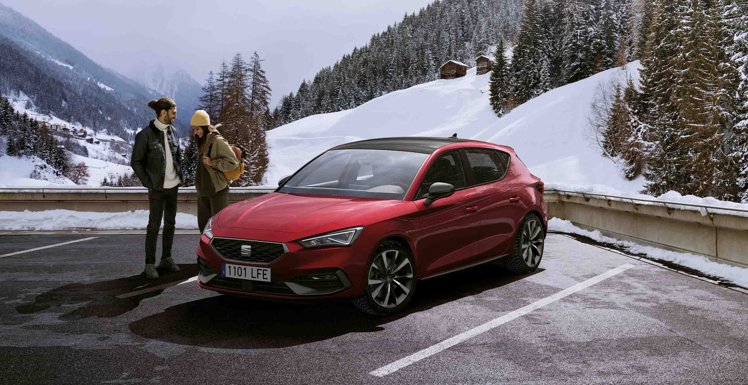 Desire red SEAT Leon hatchback, snow and mountains.